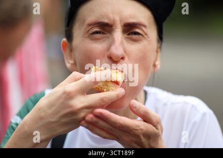 Frau isst draußen ein Stück Kuchen und genießt eine süße Leckerei Stockfoto