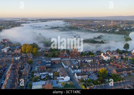 Morgenansicht von Chester, England, Großbritannien, mit Dächern, einer Kirche aus rotem Backstein, und Nebel, der über die Felder in der Nähe des Flusses Dee rollt Stockfoto