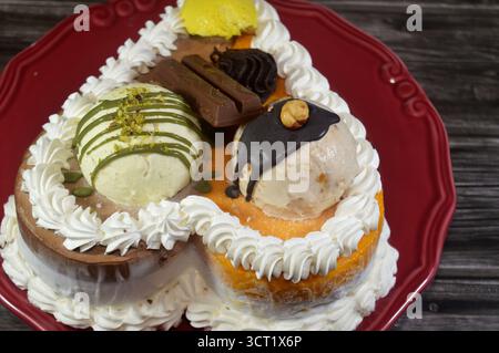 Eiskuchen mit verschiedenen Geschmacksrichtungen und einer Biskuitschicht in Eis und Schlagsahne, Mango-, Vanille- und Schokoladeneis, Stockfoto