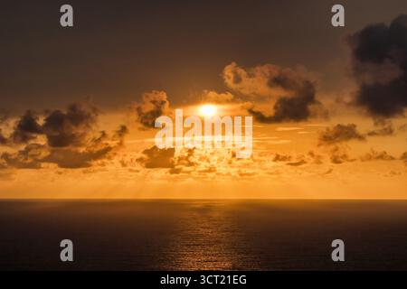 Dramatischer orangefarbener Sonnenuntergang über dem Meer mit Sonne berührendem Horizont Stockfoto