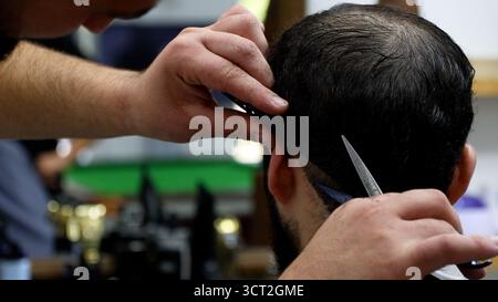Ein Mann, der von einem Friseur in einem alten Barbershop-Stuhl frisiert, Stockfoto