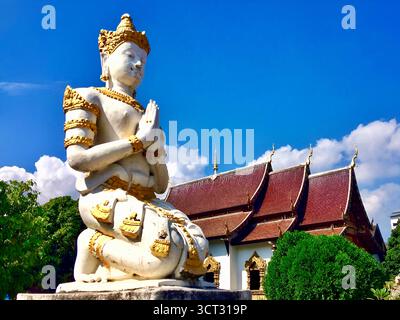 „Gebetsstatue und kunstvoll verziertes Tempeldach in Chiang Mai, Thailand – 5. Dezember 2018.“ Stockfoto