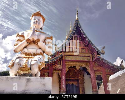 „Gebetsstatue und kunstvoll verziertes Tempeldach in Chiang Mai, Thailand – 5. Dezember 2018.“ Stockfoto