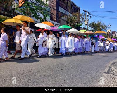 Buddhistische Gläubige in Chiang Mai, Thailand, laufen am 9. Dezember 2018 in einer Straßenprozession, gekleidet in weiße Gewänder und mit leuchtenden Regenschirmen Stockfoto