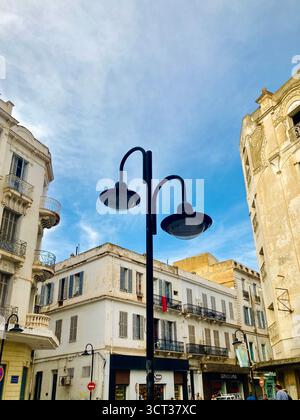 Blick auf die Straße in der alten Medina von Tunis, Tunesien. Kunstvoll verzierte Lampenpfosten, Vintage-Architektur und verschlossene Balkone. Aufgenommen am 22. September 2025. Stockfoto