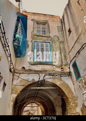 Blick auf die Straße in der alten Medina von Tunis, Tunesien. Kunstvoll verzierte Lampenpfosten, Vintage-Architektur und verschlossene Balkone. Aufgenommen am 22. September 2025. Stockfoto