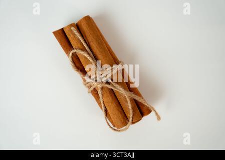 Bündel brauner Zimtstangen, die mit Juteschnur gebunden sind, isoliert auf weißem Hintergrund, Symbol für Gewürze, Kochen, Aroma und natürliche Produkte. Stockfoto