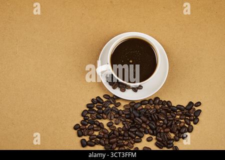 Kaffeetasse aus der Nähe, mit frisch gerösteten Bohnen auf einem rustikalen Holztisch mit Kopierraum Stockfoto