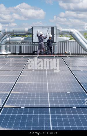 Inspektion einer Klimaanlage auf einem Dach mit Solarpaneelen Stockfoto