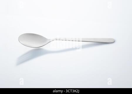 Löffel auf weißem Hintergrund mit Schirmgabel Stockfoto