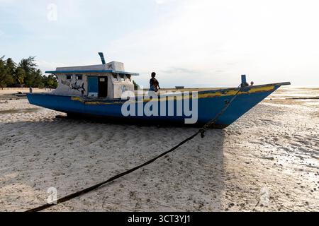 Blaues und weißes Fischerboot am Sandstrand, Insel Sumba, Indonesien Stockfoto