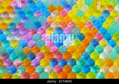 Ein buntes Mosaik aus kleinen, klaren, runden Perlen. Die Perlen sind in verschiedenen Farben und Größen erhältlich, wodurch ein lebendiges und auffälliges Muster entsteht. Konzept von p Stockfoto