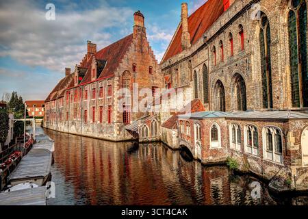 Malerischer Kanal gesäumt von historischen Backsteinbauten und Grün im mittelalterlichen Zentrum von Brügge, Belgien Stockfoto