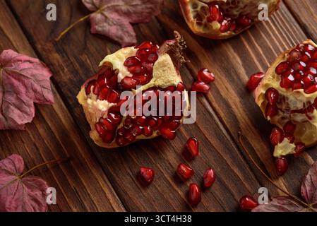 Granatapfel mit Herbstblättern auf dunklem hölzernem Hintergrund Stockfoto