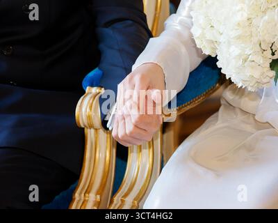 Braut und Bräutigam halten während der Hochzeitszeremonie Hände, Symbol für Liebe, Einheit und Emotionen. Stockfoto