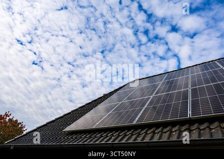 Auf einem Wohndach installierte Solaranlagen, die Sonnenlicht für nachhaltige Energie unter hellem, bewölktem Himmel nutzen Stockfoto