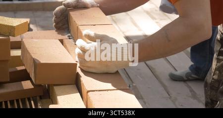 Ein Mann baut eine Ziegelmauer. Backstein auf die Lösung. Bau eines Ziegelhauses. Stockfoto