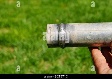 Metallrohr mit einer Schweißnaht in der Hand des Menschen des Schweißers Stockfoto