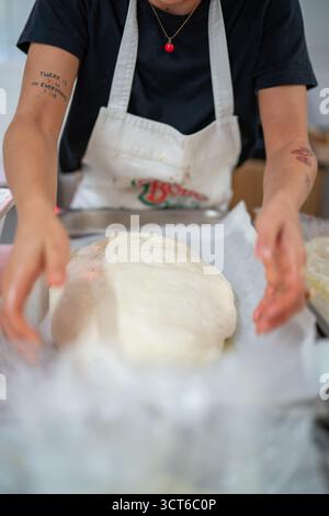 Piacenza, Italien - 25. September 2025 Junge kaukasische Frau bastelt authentischen italienischen Teig für handwerkliche Focaccia und Pizza in einer professionellen Küche Stockfoto
