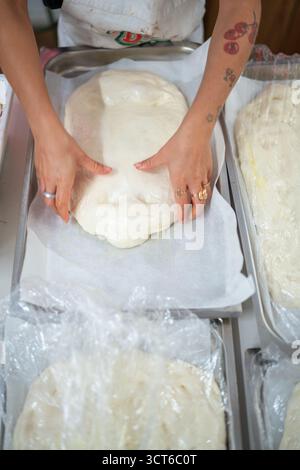 Piacenza, Italien - 25. September 2025 die junge Kaukasierin bereitet in einer professionellen Handwerkerin auf fachkundige Weise Teig für authentische italienische Focaccia und Pizza zu Stockfoto