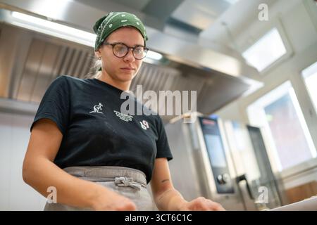 Piacenza, Italien - 25. September 2025 engagierte Unternehmerin fertigt sorgfältig authentische italienische kulinarische Kreationen in einem modernen Profi Stockfoto