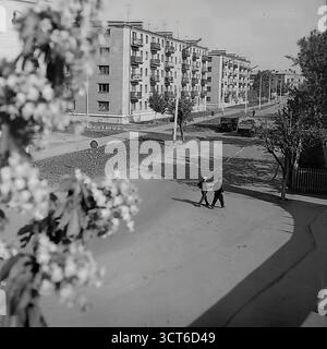 Ein Panoramablick auf ein neu erbautes Wohnviertel in Sloviansk, ukrainische SSR, während der 1960er Jahre Die Fotos zeigen den Puschkin Boulevard (heute Shevchenko Boulevard), eine breite Allee mit einer zentralen Fußgängerpromenade. Die Szene wird von Reihen typischer fünfstöckiger „Chruschtschjowka“-Wohnhäuser dominiert, ein Markenzeichen der sowjetischen Massenhäuser dieser Zeit. Junge Bäume und spärliche Landschaftsgärten deuten auf die jüngste Fertigstellung des Bezirks hin. Fußgänger schlendern entlang der Promenade und erwecken die moderne Stadtlandschaft zum Leben. Dieses Bild spiegelt den Geist der sowjetischen Stadtentwicklung und den Optimismus wider Stockfoto