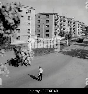 Ein Panoramablick auf ein neu erbautes Wohnviertel in Sloviansk, ukrainische SSR, während der 1960er Jahre Die Fotos zeigen den Puschkin Boulevard (heute Shevchenko Boulevard), eine breite Allee mit einer zentralen Fußgängerpromenade. Die Szene wird von Reihen typischer fünfstöckiger „Chruschtschjowka“-Wohnhäuser dominiert, ein Markenzeichen der sowjetischen Massenhäuser dieser Zeit. Junge Bäume und spärliche Landschaftsgärten deuten auf die jüngste Fertigstellung des Bezirks hin. Fußgänger schlendern entlang der Promenade und erwecken die moderne Stadtlandschaft zum Leben. Dieses Bild spiegelt den Geist der sowjetischen Stadtentwicklung und den Optimismus wider Stockfoto