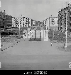 Ein Panoramablick auf ein neu erbautes Wohnviertel in Sloviansk, ukrainische SSR, während der 1960er Jahre Die Fotos zeigen den Puschkin Boulevard (heute Shevchenko Boulevard), eine breite Allee mit einer zentralen Fußgängerpromenade. Die Szene wird von Reihen typischer fünfstöckiger „Chruschtschjowka“-Wohnhäuser dominiert, ein Markenzeichen der sowjetischen Massenhäuser dieser Zeit. Junge Bäume und spärliche Landschaftsgärten deuten auf die jüngste Fertigstellung des Bezirks hin. Fußgänger schlendern entlang der Promenade und erwecken die moderne Stadtlandschaft zum Leben. Dieses Bild spiegelt den Geist der sowjetischen Stadtentwicklung und den Optimismus wider Stockfoto