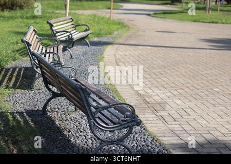 Schmiedeeiserne Parkbänke im Freien an sonnigen Tagen. Für bequeme Sitze und Entspannung. Ideal für Parks und öffentliche Bereiche. Stockfoto