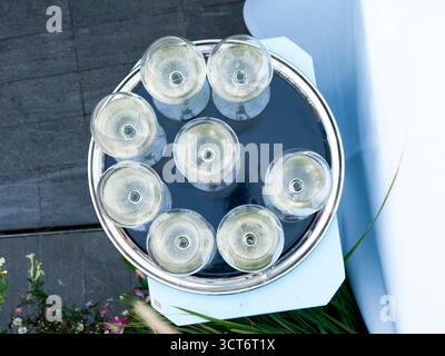 Weißweingläser auf einem silbernen Tablett während einer Firmenveranstaltung auf dem Dach in Paris, elegante und festliche Atmosphäre. Stockfoto
