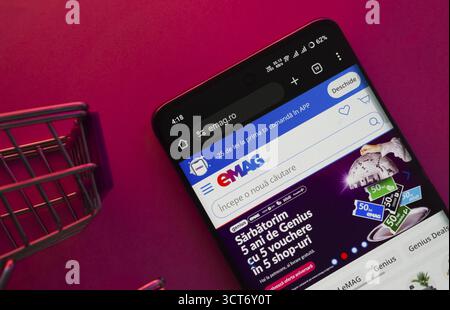 Dhaka, Bangladesch- 03. Oktober 2025: Ein Smartphone, das die EMAG-Website mit einem Einkaufswagen zeigt, wird auf einem lebendigen Hintergrund gezeigt Stockfoto