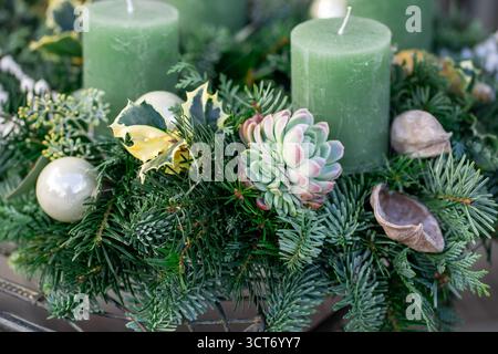 Der Weihnachtskerzenkranz ist ein festliches Arrangement aus natürlichen Elementen wie Sukkulenten, Tannenzweigen, kombiniert mit Kerzen. Stockfoto