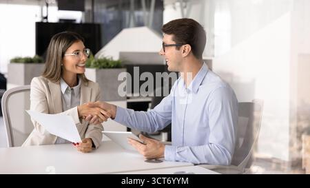 Ein paar glückliche junge lateinische Geschäftspartner, die sich die Hand schütteln Stockfoto