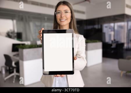 Glückliche junge Geschäftsfrau, die einen leeren Bildschirm auf dem Tablet zeigt Stockfoto