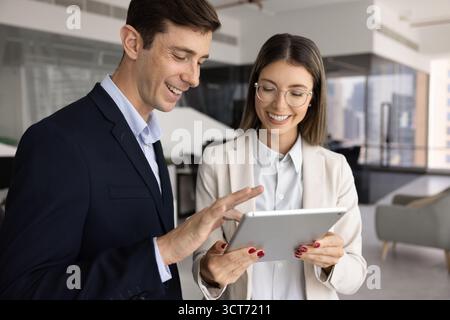 Positive Kollegen, die Tablets verwenden, um Ideen für Projekte und Tippen auszutauschen Stockfoto