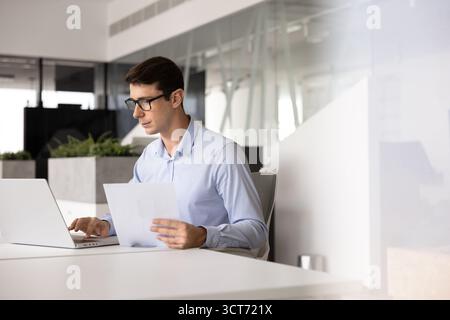 Ernsthafter hispanischer Experte in Brille, der an Dokumenten arbeitet Stockfoto