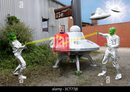 Aus dem FARBKÖRPER Kalender 2026 - Bodypainting Variationen: UFO Photoshooting mit Paul Skupin und Maria Skupin als Außerirdische und Tschiponnique Skupin als Redshirt nach einer Landung auf einem Industriegelände auf dem Planeten Erde in Bakede als Teil des Projekts Geek Art des Fotografen Tschiponnique Skupin und des Bodypainters und Transformakers Enrico Lein. *** Aus dem FARBKÖRPER Kalender 2026 Bodypainting Variations UFO Fotoshooting mit Paul Skupin und Maria Skupin als Außerirdische und Tschiponnique Skupin als Redshirt nach einer Landung auf einem Industriegelände auf dem Planeten Erde in Bakede als Teil von t Stockfoto