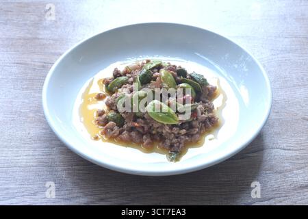 Scharfe gebratene Schweinekoteletts mit Bohnen in Garnelenpaste Curry thailändische Südstaaten-Gerichte auf Teller Stockfoto