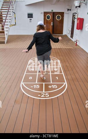 Viladecans. Spanien - 03. Oktober 2025: Ein Passagier genießt die Freizeitaktivitäten an Bord eines Schiffes und nimmt an einem Hopscotch-ähnlichen Spiel Teil, das gemalt ist Stockfoto