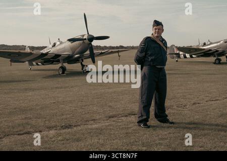 RAF-Sergeant in Zeituniform, der neben den Spitfire-Flugzeugen auf dem Duxford-Flugplatz steht Stockfoto