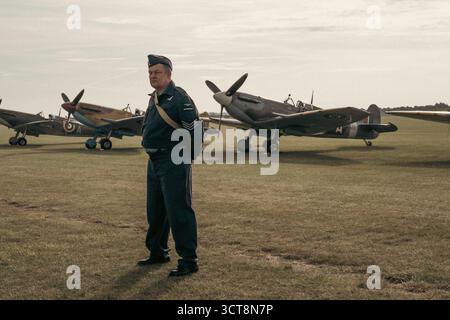 RAF-Sergeant in Vintage-Uniform mit Spitfire-Kämpfern auf dem historischen Flugplatz Stockfoto