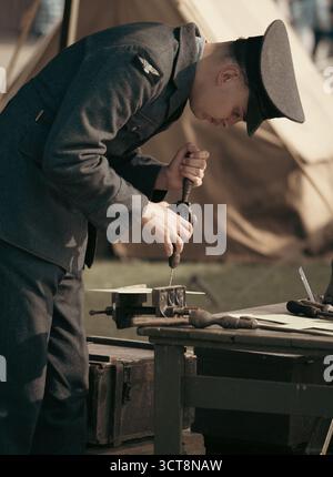 RAF-Handwerker in zeitlicher Uniform, der mit Handbohrer an einer Vintage-Werkbank arbeitet Stockfoto