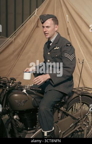 RAF Sergeant in Kriegsuniform mit Vintage-Motorrad im Militärlager Stockfoto