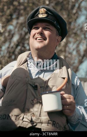 RAF-Pilot in Uniform lächelnd, während er einen Emailbecher auf der Duxford Airshow hält Stockfoto