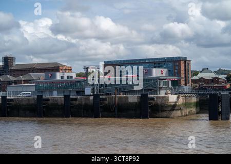 Modernes Fährhafen-Gebäude mit Glasfassade mit Blick auf das Hafenwasser unter bewölktem Himmel Stockfoto