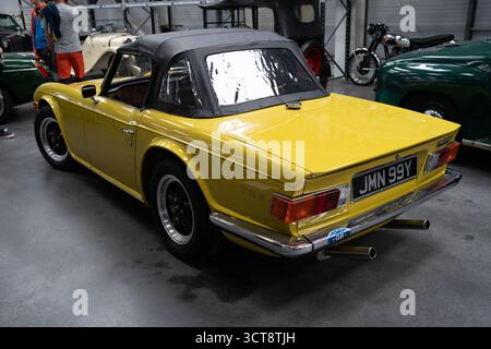 Klassischer gelber Triumph TR6 Cabriolet in Garage mit schwarzem Verdeck Stockfoto