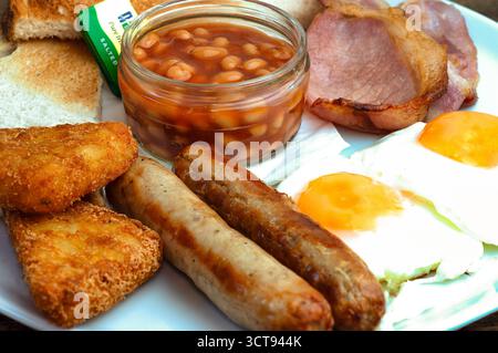 Genießen Sie ein herzhaftes englisches Frühstück! Toast, Bohnen, Wurst, Eier, Speck, und Kartoffelrösti - Treibstoff für den Tag! Stockfoto