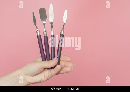 Ein Mädchen hält einen 4Piece Cake Cream Spatel auf rosa Hintergrund. Stockfoto