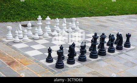 Riesiges Freiluftschach auf dem gepflasterten Steinplatz mit Schwarz-weiß-Figuren Stockfoto