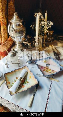 Luxuriöse Vintage-Tischdekoration mit silbernem Samovar, Kerzen und antiken Tellern Stockfoto